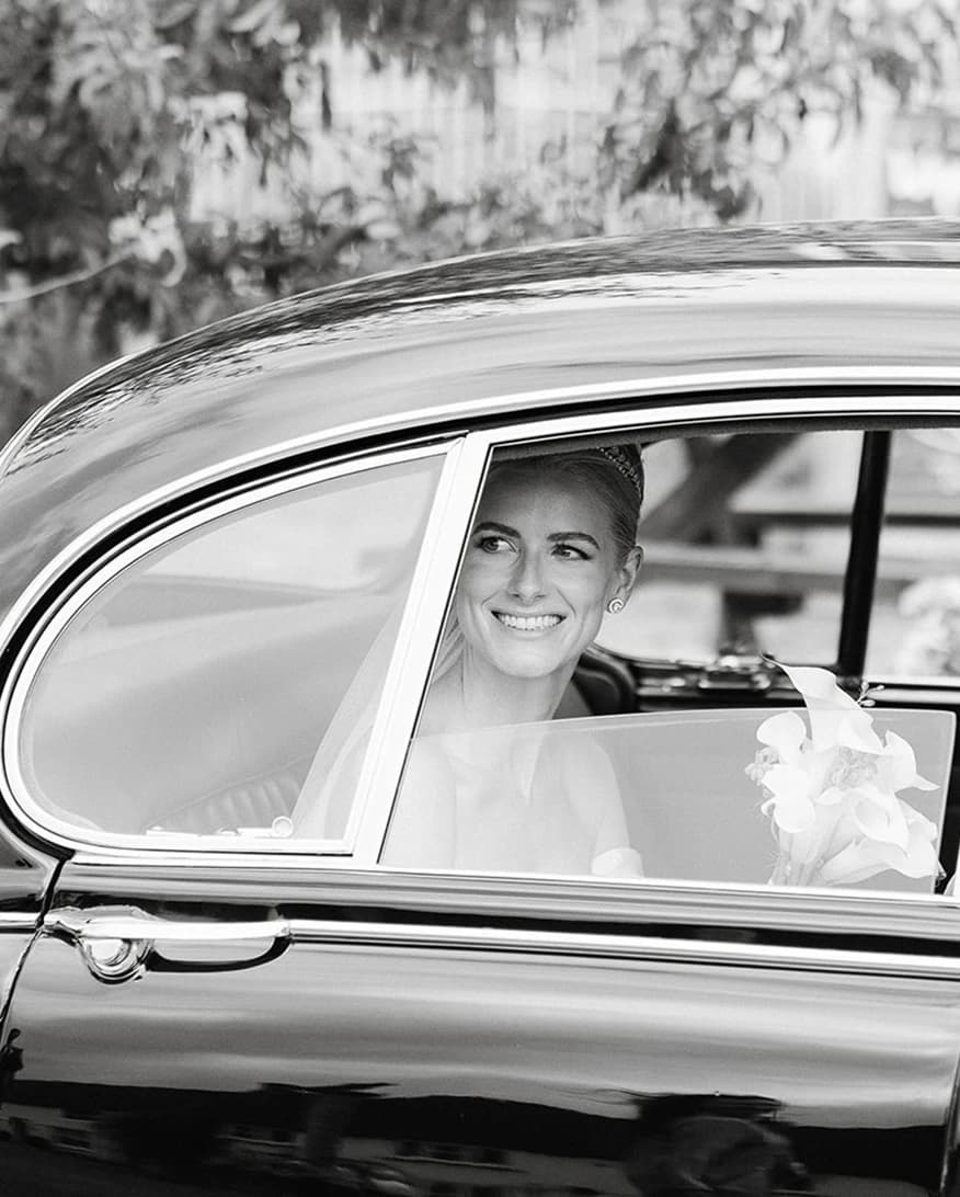 Smiling bride peeks outside the vintage car windonw