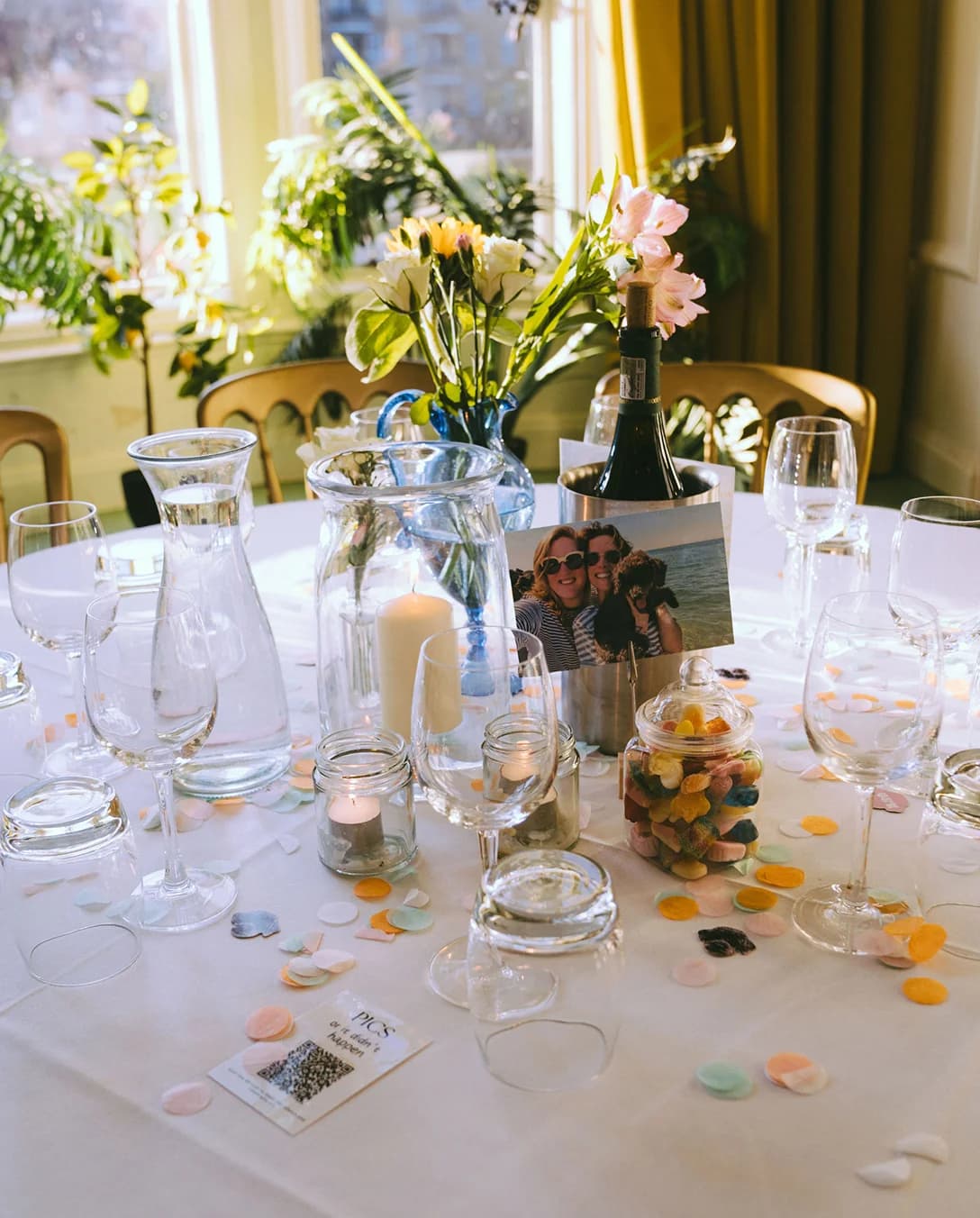 A table decorated with candles, flowers, personal photos and confetti
