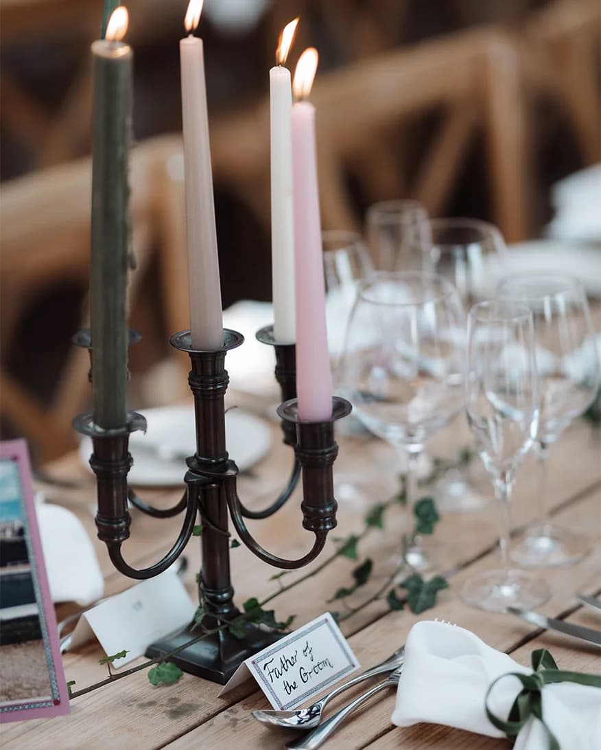 Autumnal table décor detail showing candleholders with green, pink and cream candlesticks