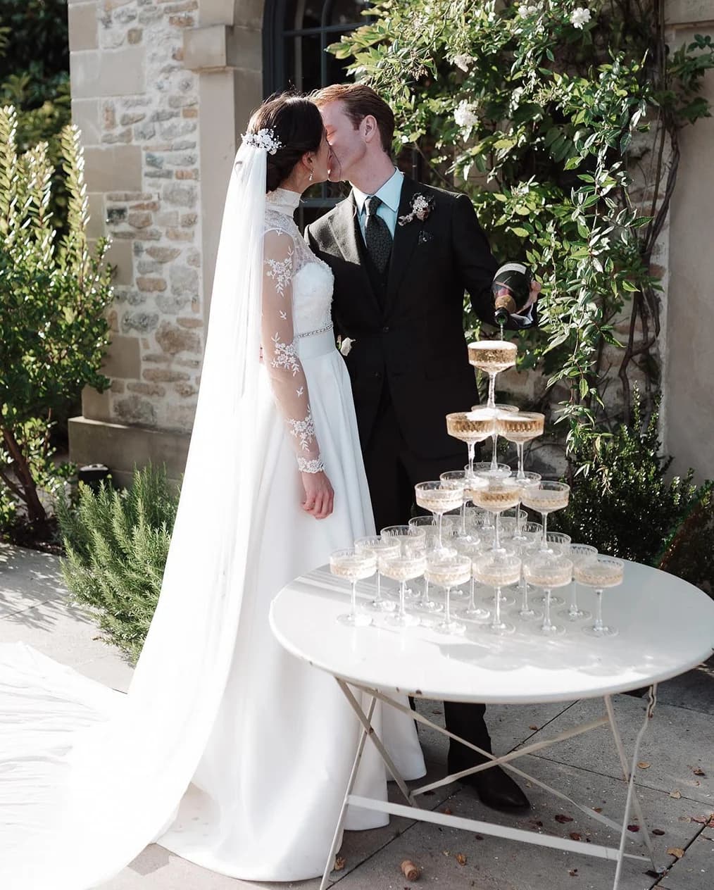 Bride and groom pour champagne over the coupe glass tower