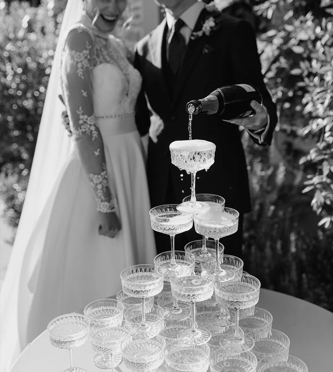 Bride and groom pour champagne over glass tower
