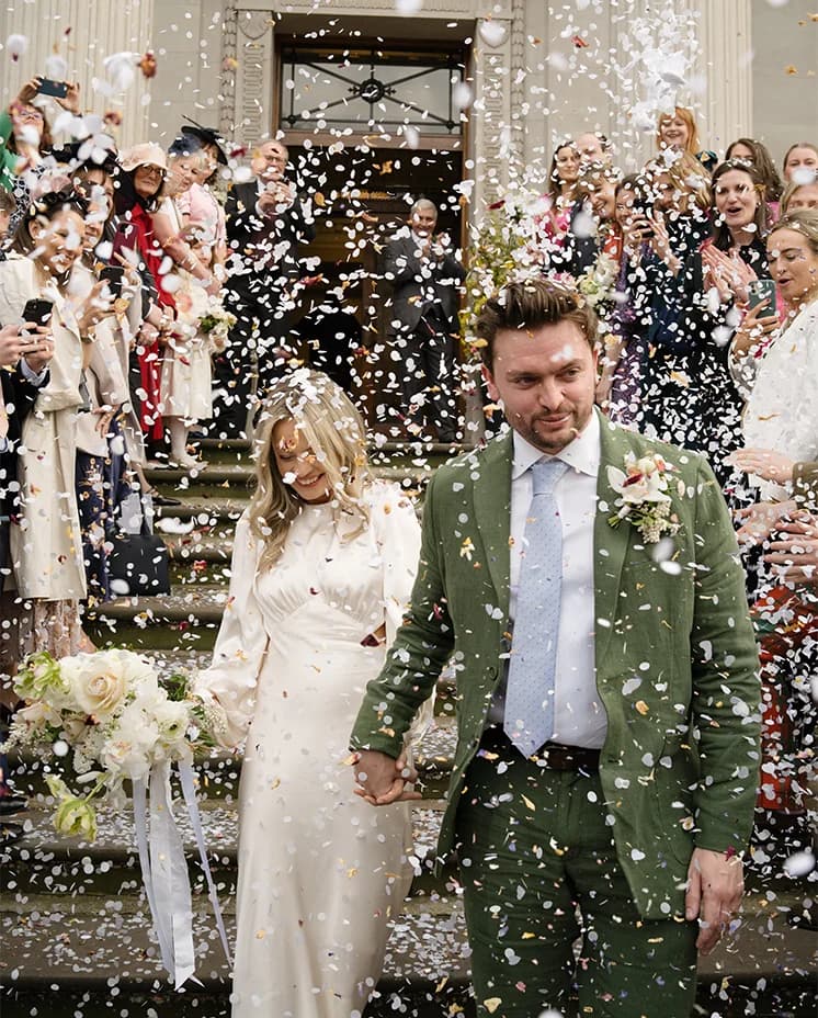 Bride and groom leave the Old Marylebone Town Hall after their ceremony, while guests throw confetti