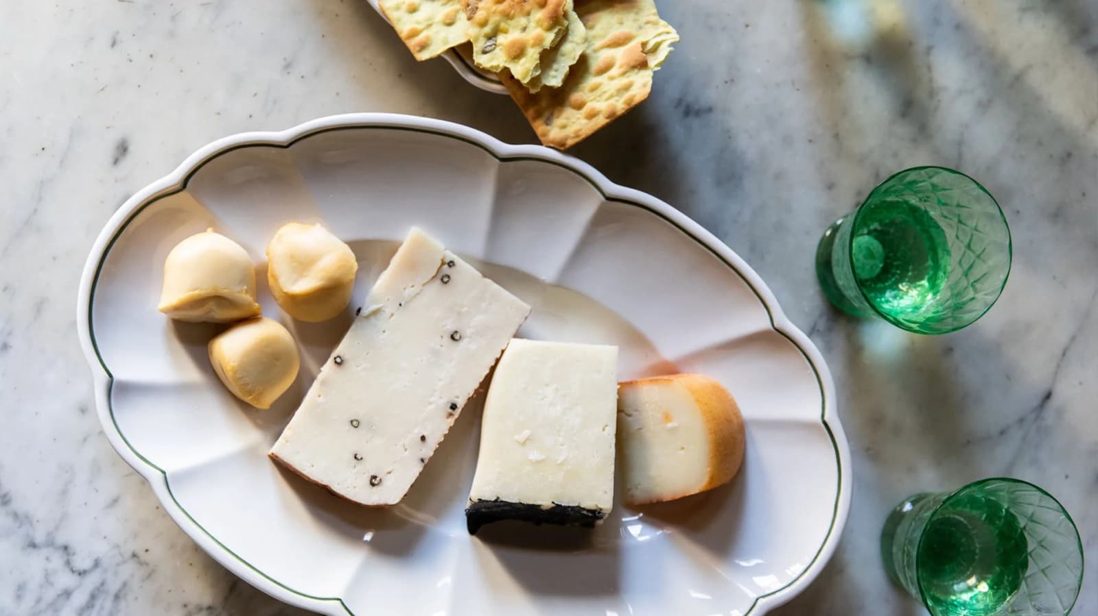 A selection of cheese served on Skye McAlpine scalloped serving platter with green border