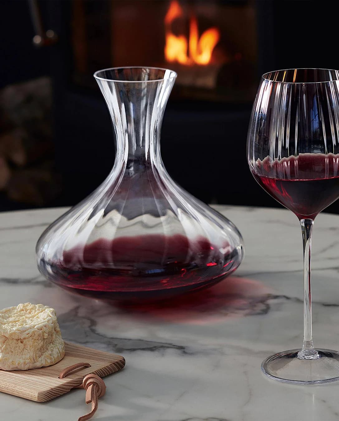 Red wine decanting in glass carafe next to fireplace