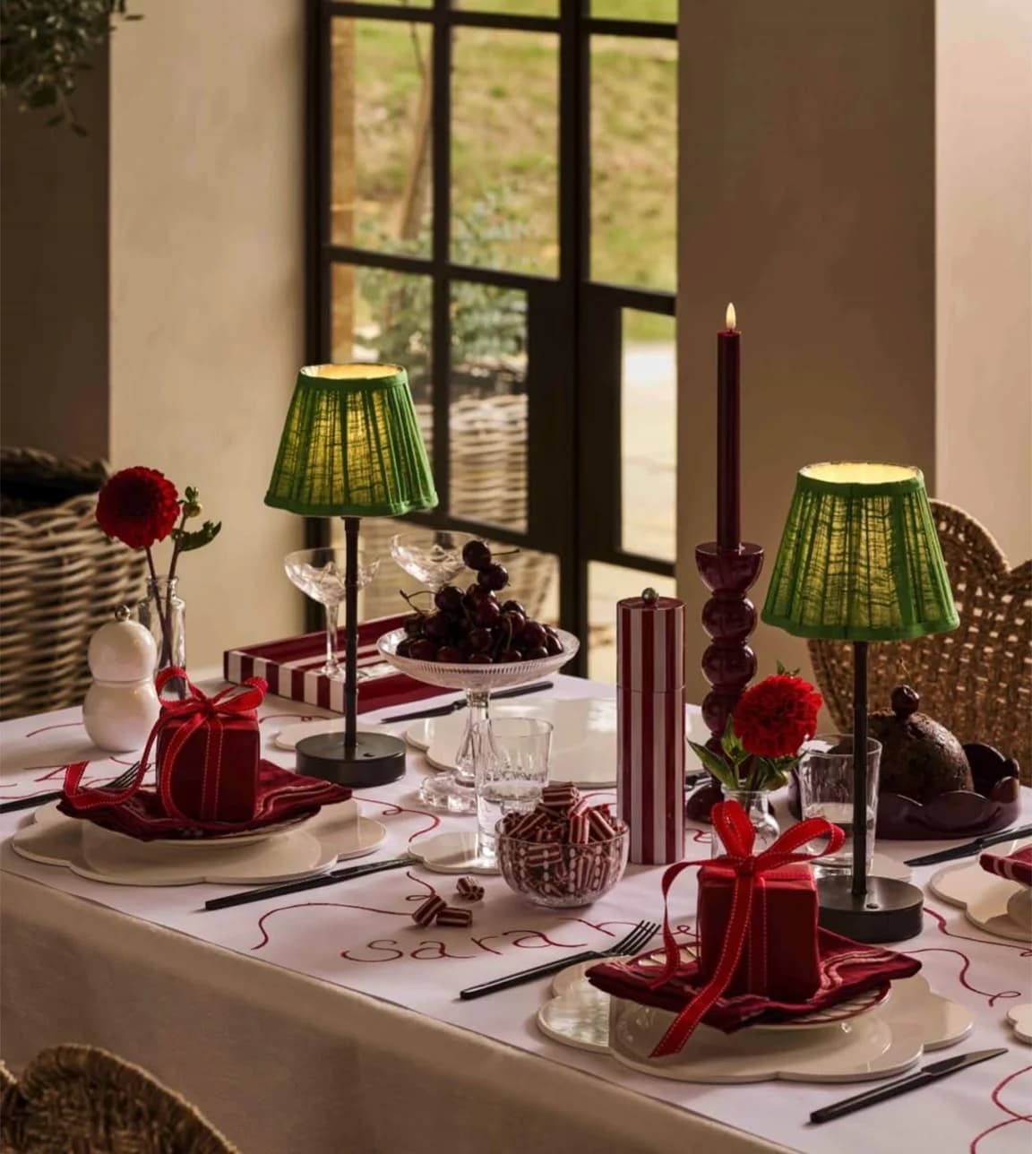 Beautifully set Christmas table featuring lamps, red table décor and bows