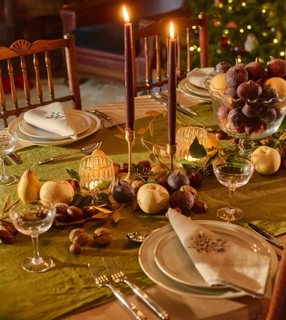 A decorated Christmas table set with cutlery, florals, plates and champagne coupes