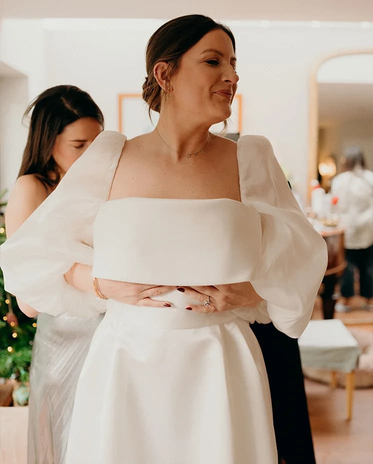 Bridesmaids helps bride to put on the dress