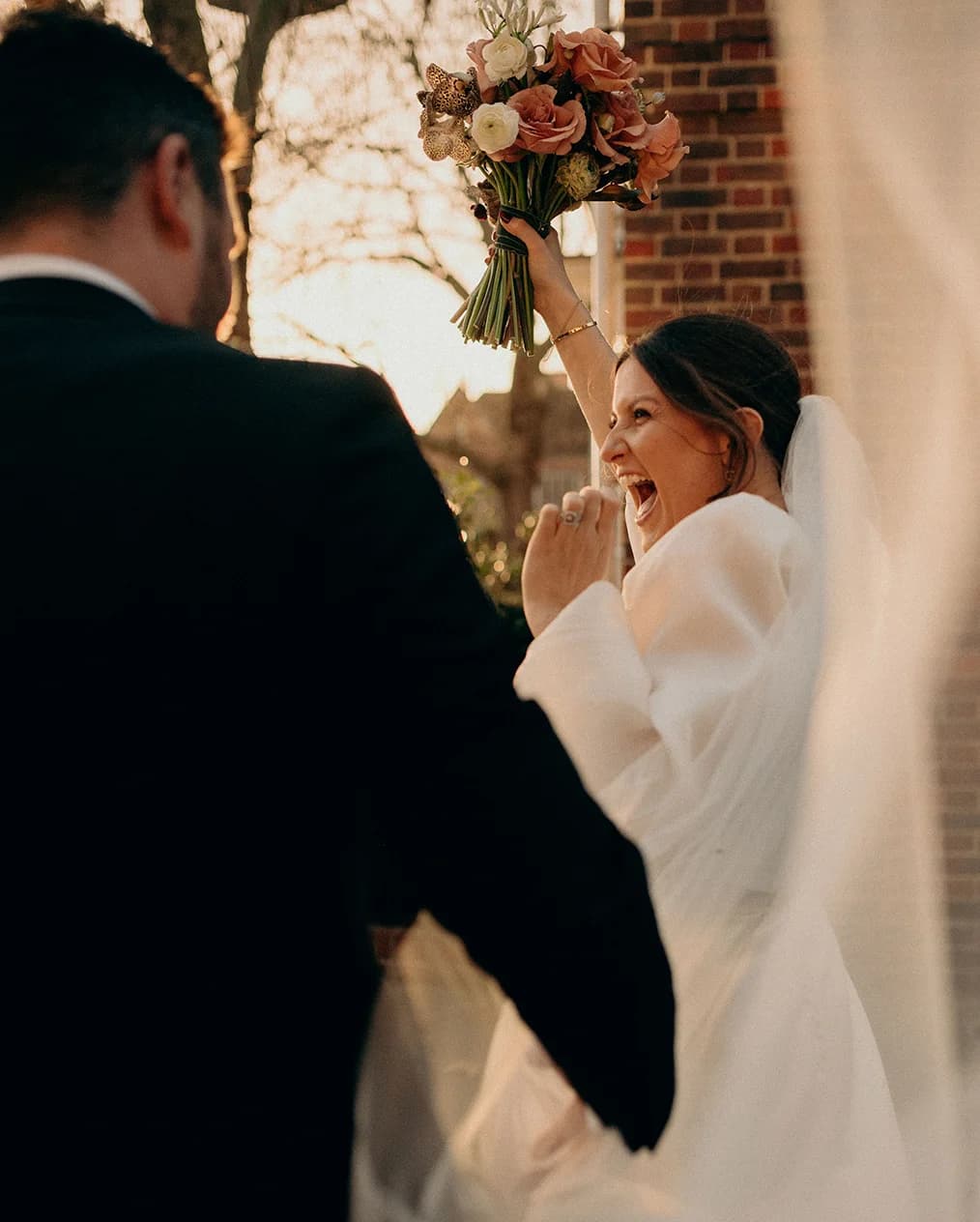 Bride raises her hand with winter wedding flower bouquet in hand