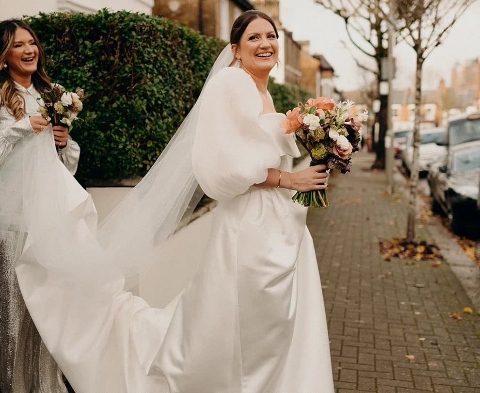 Bride stands on a street, wearing her Jesus Peiro gown and veil