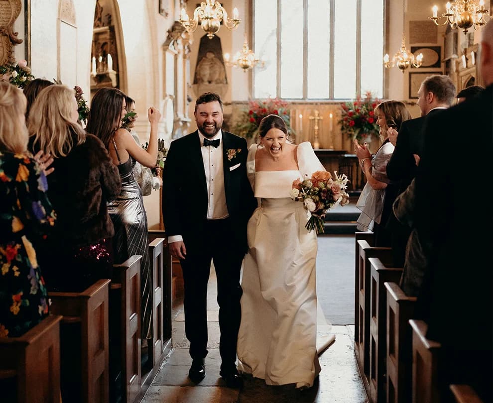 Happy bride and groom walk down the aisle after their wedding ceremony inside Chelsea Old Church