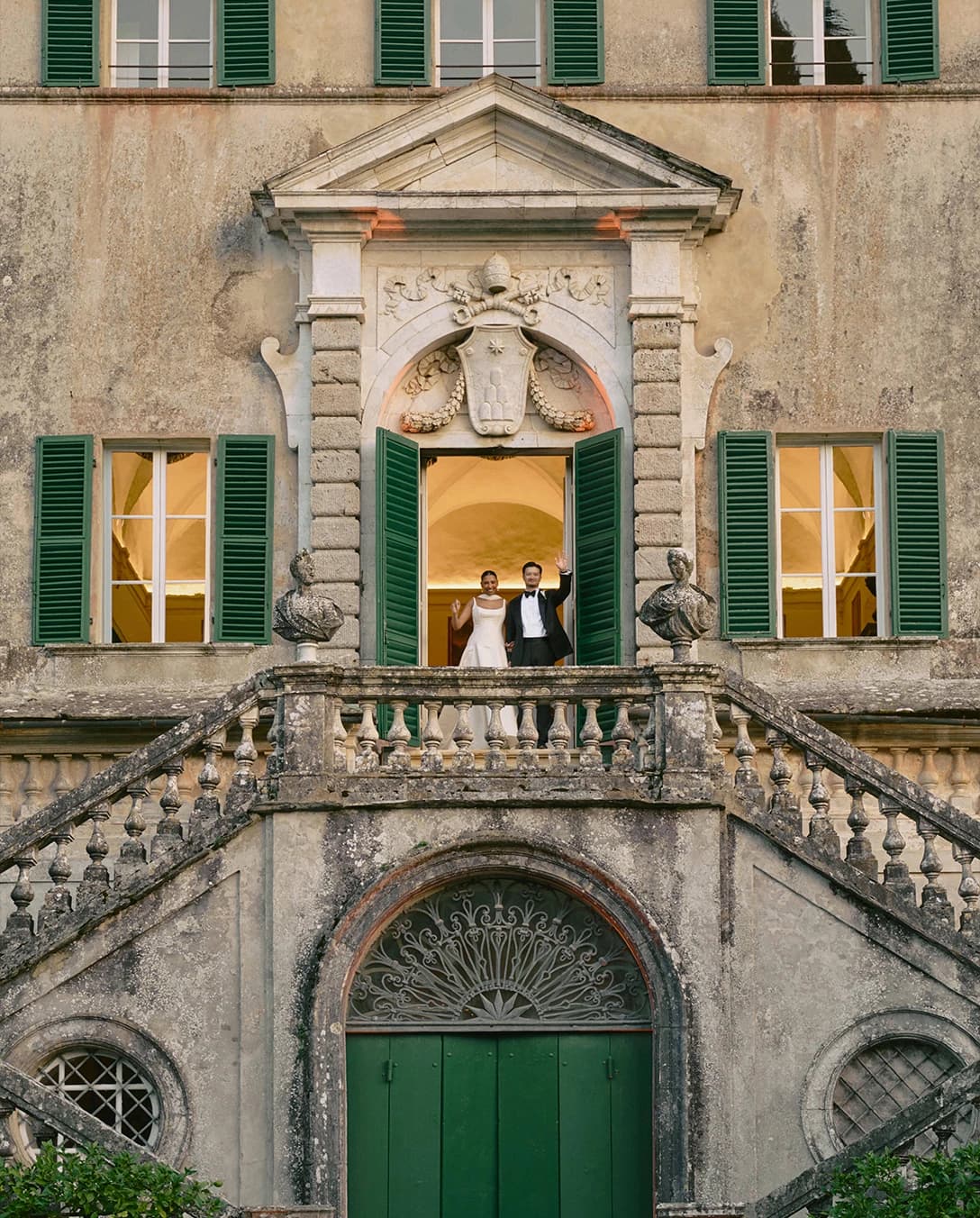 Bride and groom stand on Villa Centinale's balcony waving