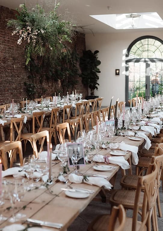 Elegant wedding reception tables at Middleton Lodge with rustic wooden chairs, floral greenery, and candlelit place settings.