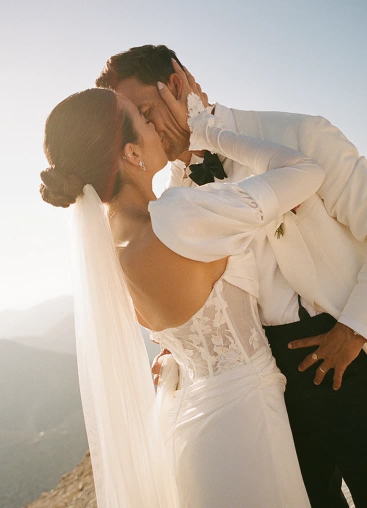 Bride and groom sharing a romantic kiss in soft golden light during an intimate wedding on a Greek island.  Select 81 more words to run Humanizer.