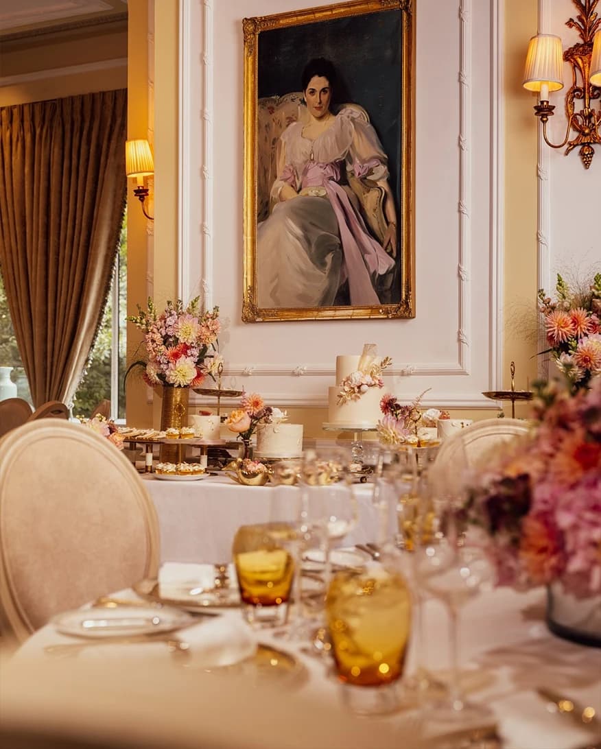 Elegant wedding reception at The Savoy London with floral table décor, wedding cake display, and classic portrait backdrop