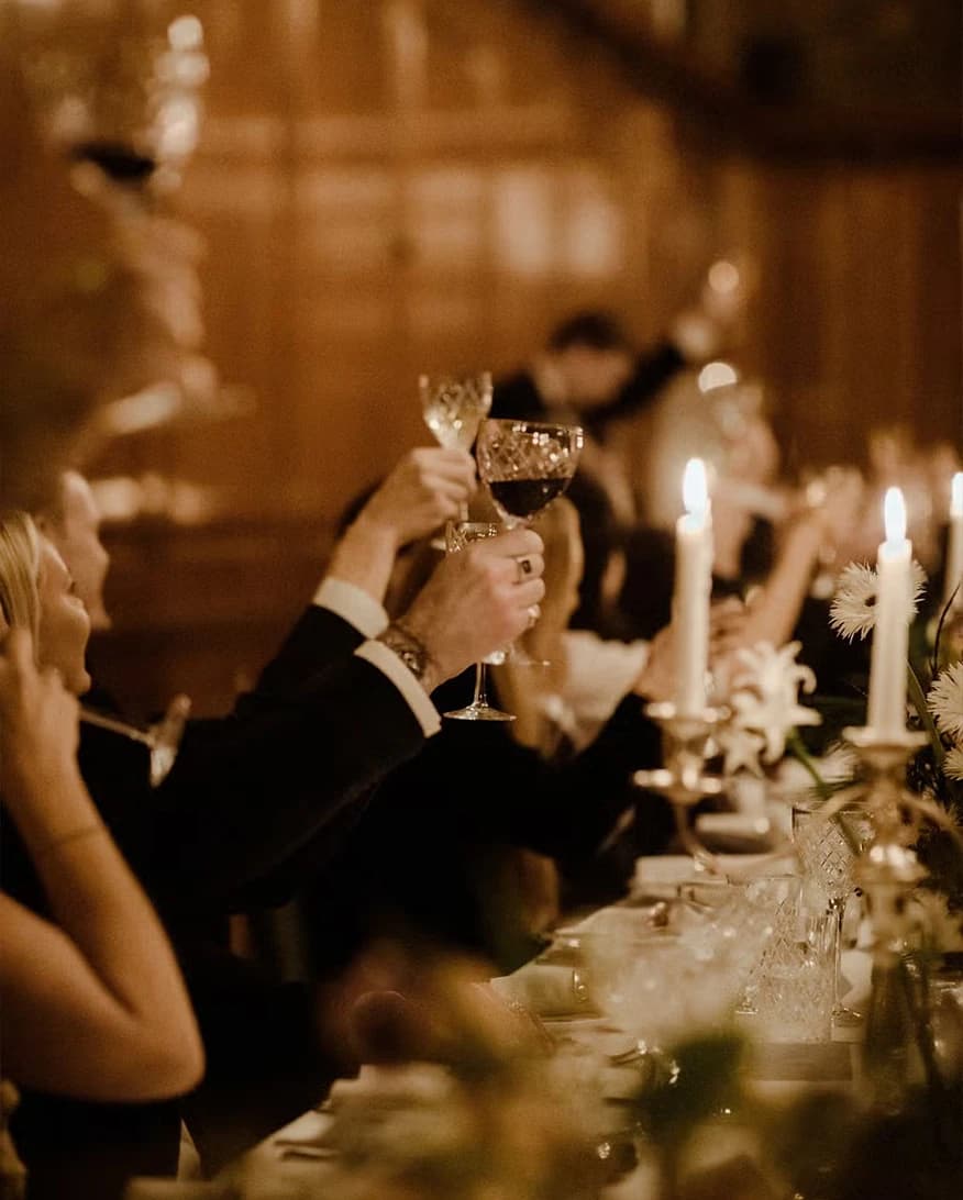 Wedding guests toasting at The Ned London during a candlelit reception with elegant table settings and warm ambience