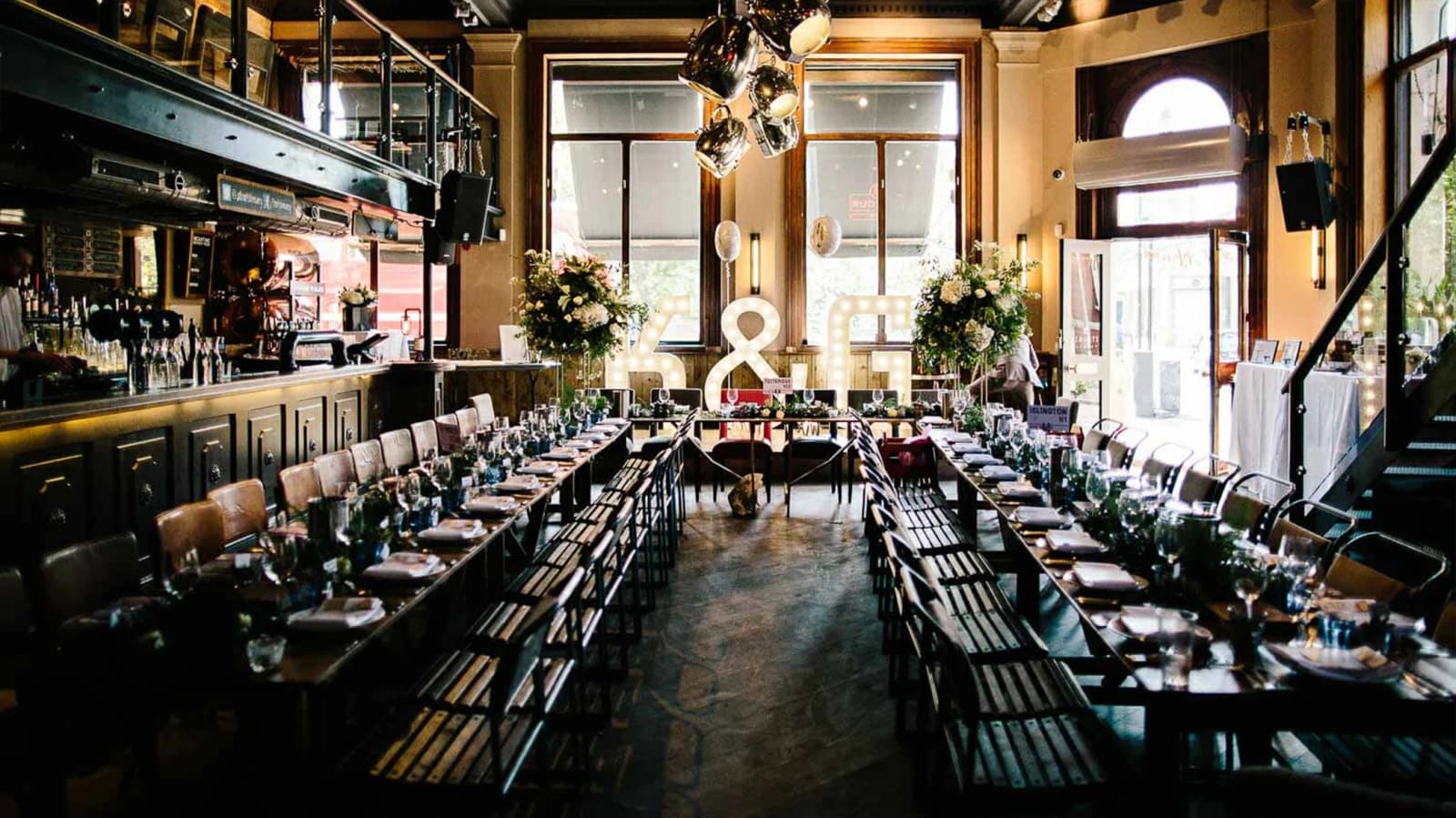 Wedding reception at Balfour St Barts London with long banquet tables, industrial-chic interior, and illuminated initials décor