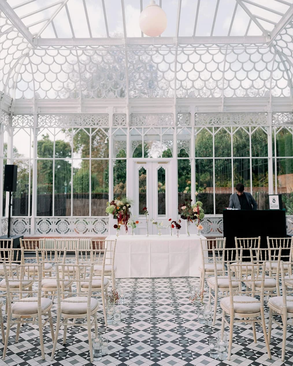 Wedding ceremony at Horniman House & Gardens London in a glass conservatory with aisle seating and floral arrangements