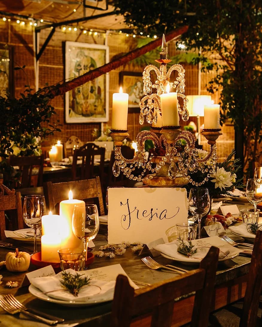 Wedding reception table at Petersham Nurseries London with candlelight, chandelier centrepiece, and rustic garden setting