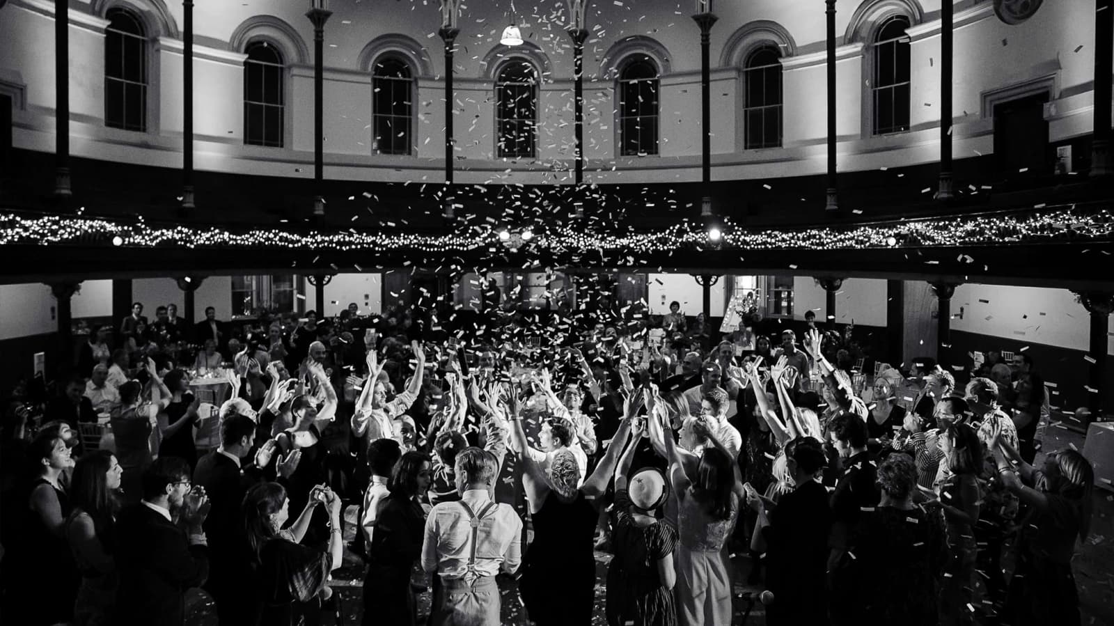 Wedding celebration at Round Chapel Hackney London with guests dancing under confetti in a grand historic hall