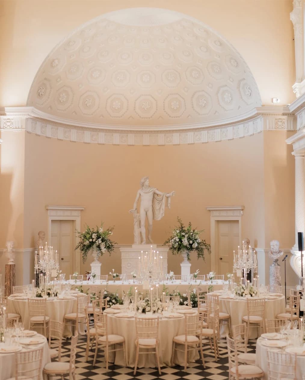 Wedding reception at Syon Park Great Hall London with classical statue, domed ceiling, and elegant candlelit tables
