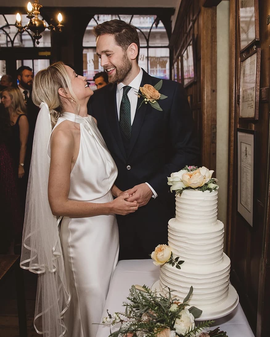 Bride and groom at Berry Bros. & Rudd London wine cellar with wedding cake and intimate reception setting