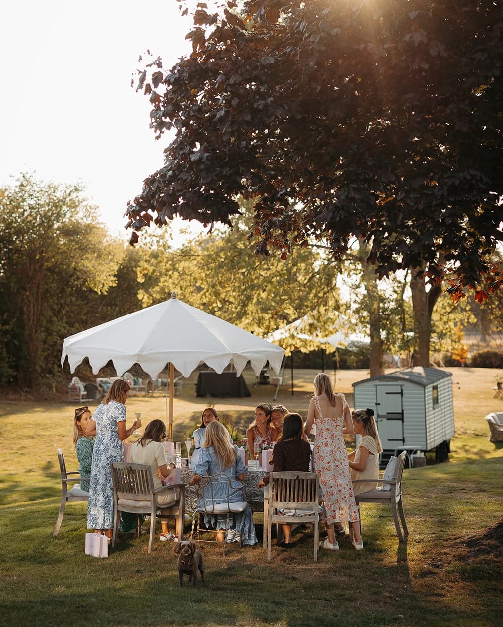 Guests dining al fresco at an elegant garden rehearsal dinner, celebrating together before the wedding day.