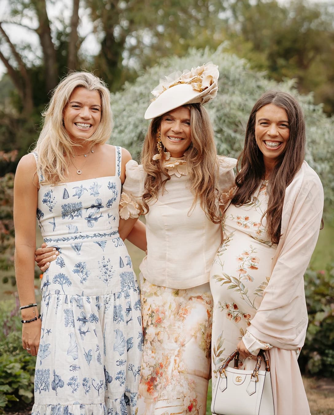 Annabel Croft and her daughter are posing together in a garden, wearing floral occasionwear at a luxury countryside wedding.