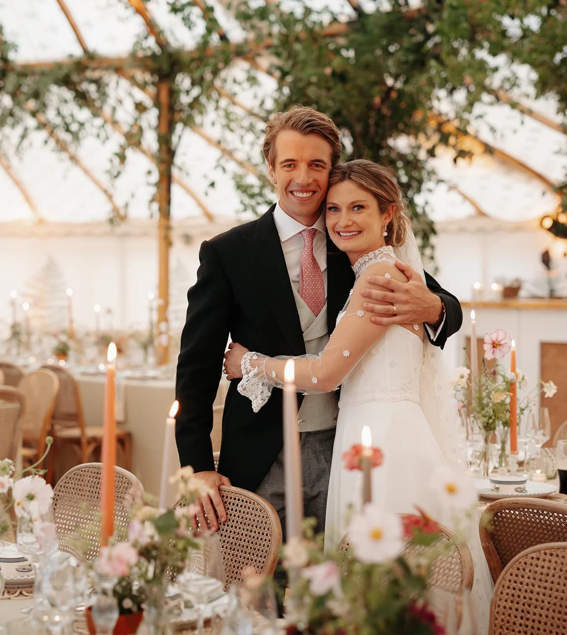 Honour & Charlie admiring their beautifully styled wedding reception marquee, featuring elegant tablescapes, candlelight and abundant countryside floral arrangements.