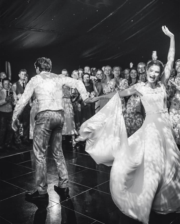 Bride and groom dance their first dance together while being surrounded by guests