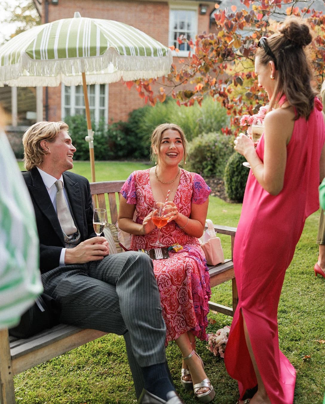 Wedding guests enjoying drinks and conversation in the garden during an English countryside wedding reception on a sunny afternoon.
