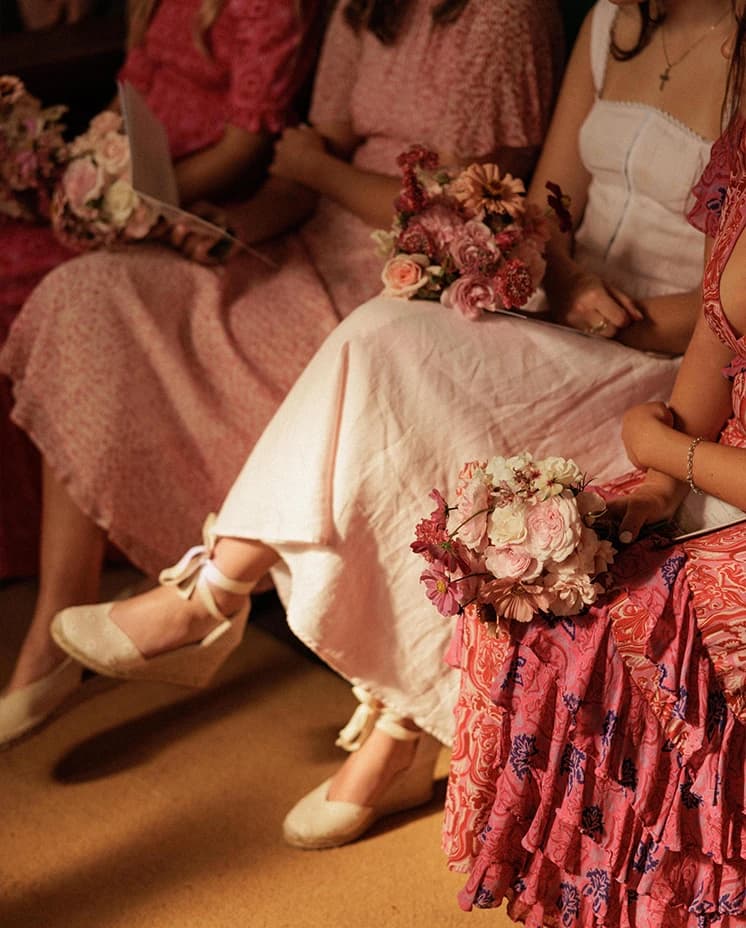 Bridesmaids holding pink and blush bouquets during an English countryside church wedding ceremony, wearing elegant pink dresses with coordinated floral arrangements.