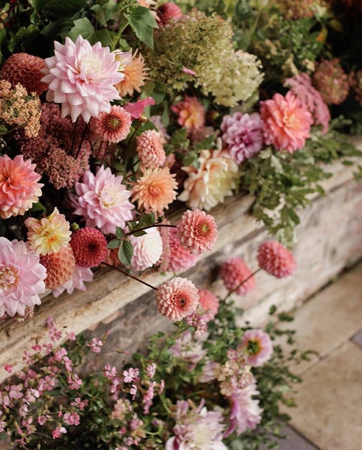 Lush pink and blush wedding floral arrangements featuring dahlias, hydrangeas and seasonal blooms, creating a romantic display for an English countryside wedding. 