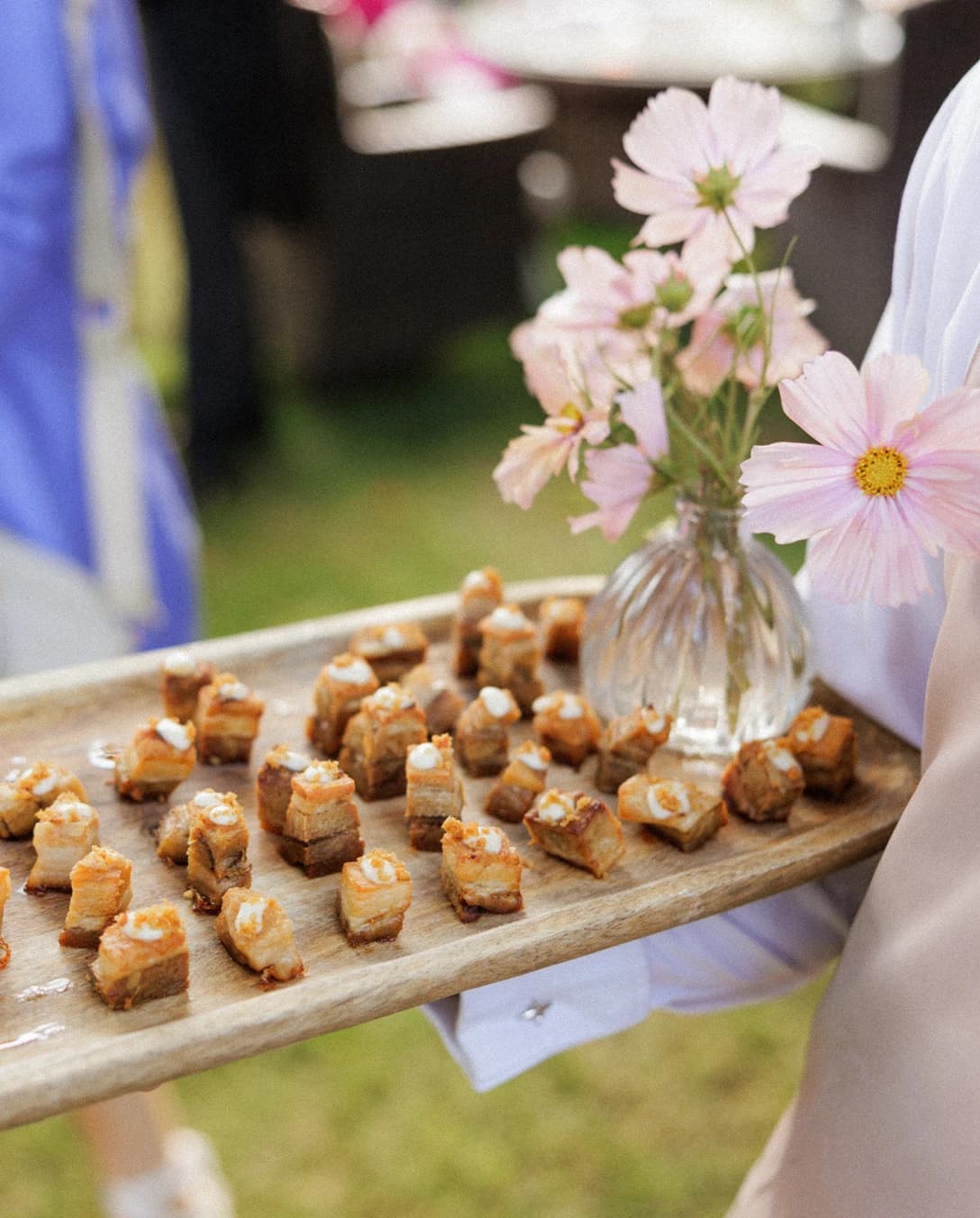 Canapés served on a rustic wooden tray with delicate floral styling, creating an elegant outdoor cocktail hour at an English countryside wedding reception.