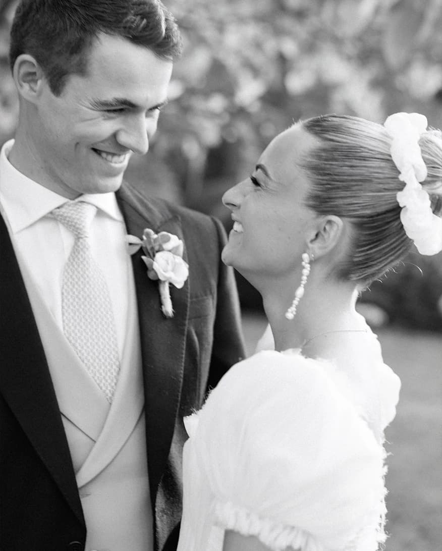 Bride and groom sharing a joyful golden hour portrait at their romantic Hampshire countryside wedding, captured in an elegant black and white photograph.
