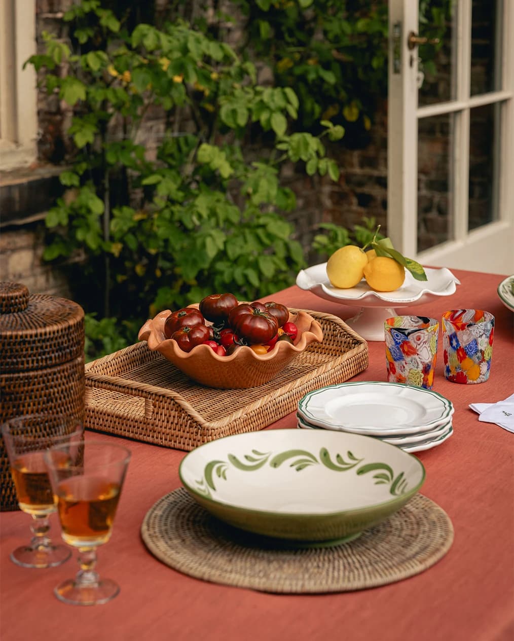 Outdoor tablescape with tableware pieces places on terracotta tablecloth