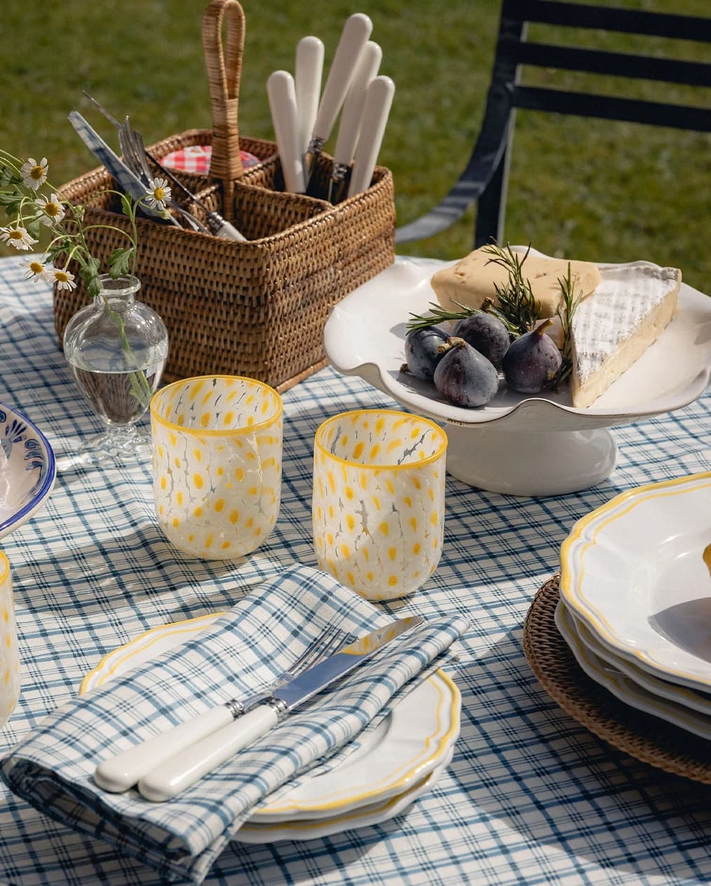 An outdoor tablescape with tableware wedding gifts placed on blue tablecloth
