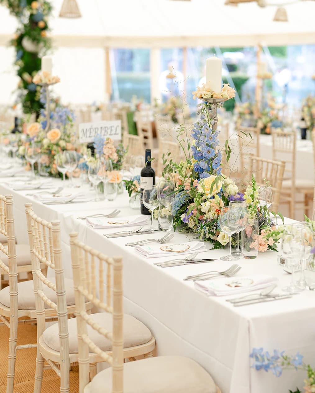 Long wedding tables in marquee, decorated with colourful flowers