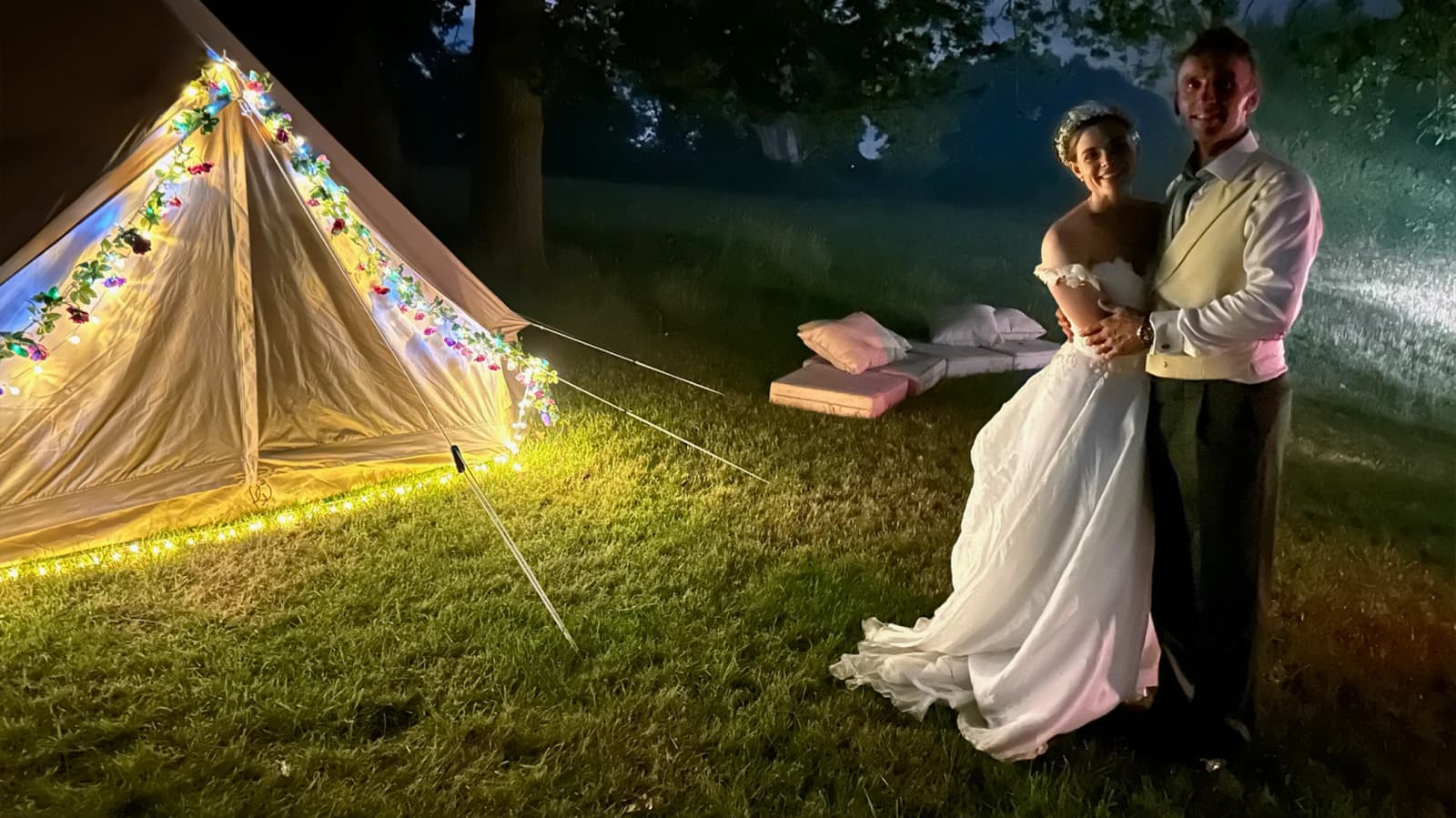 Bride and groom stand next to a tent post-wedding accommodation