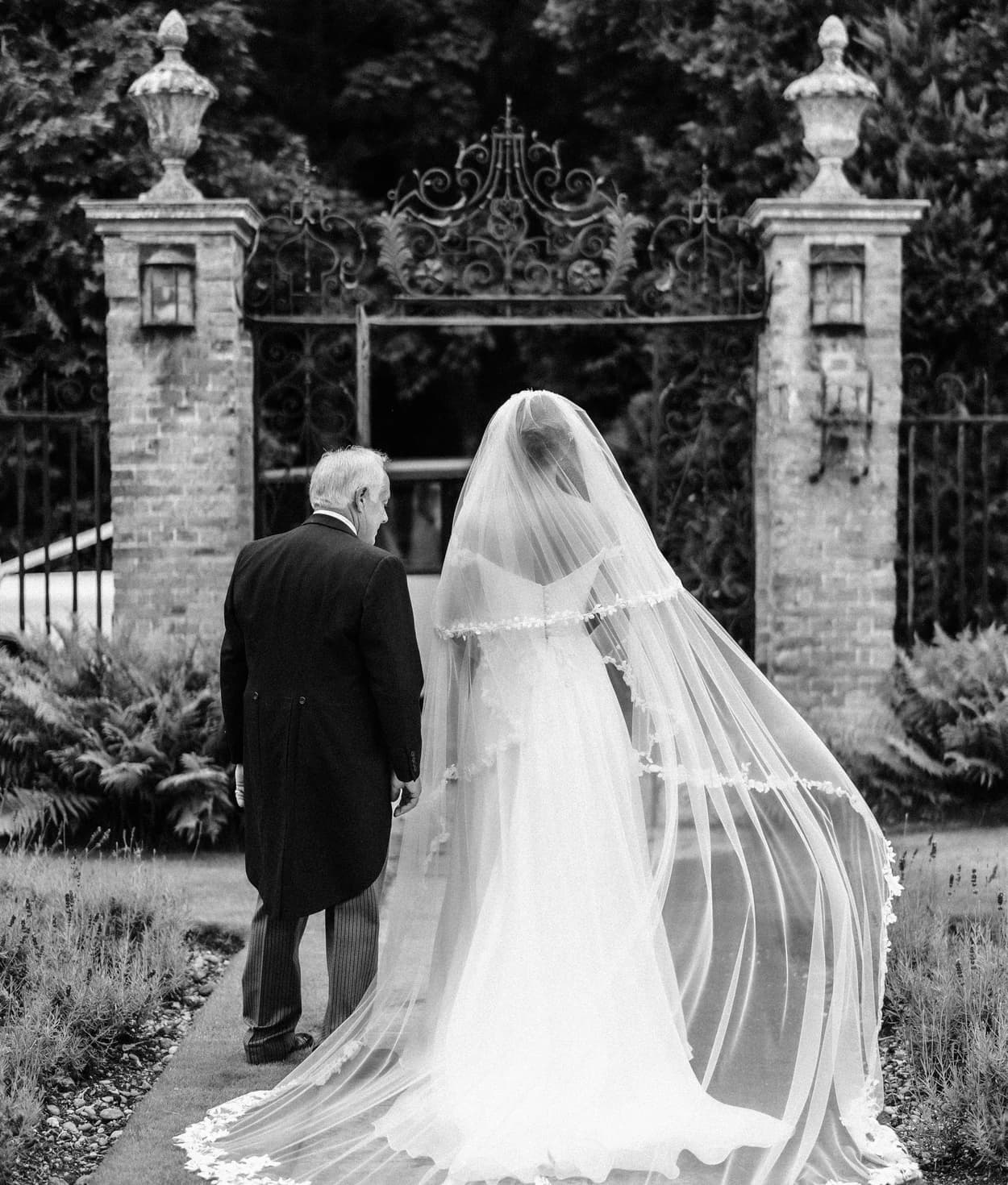 Bride and father of the bride walk in the garden