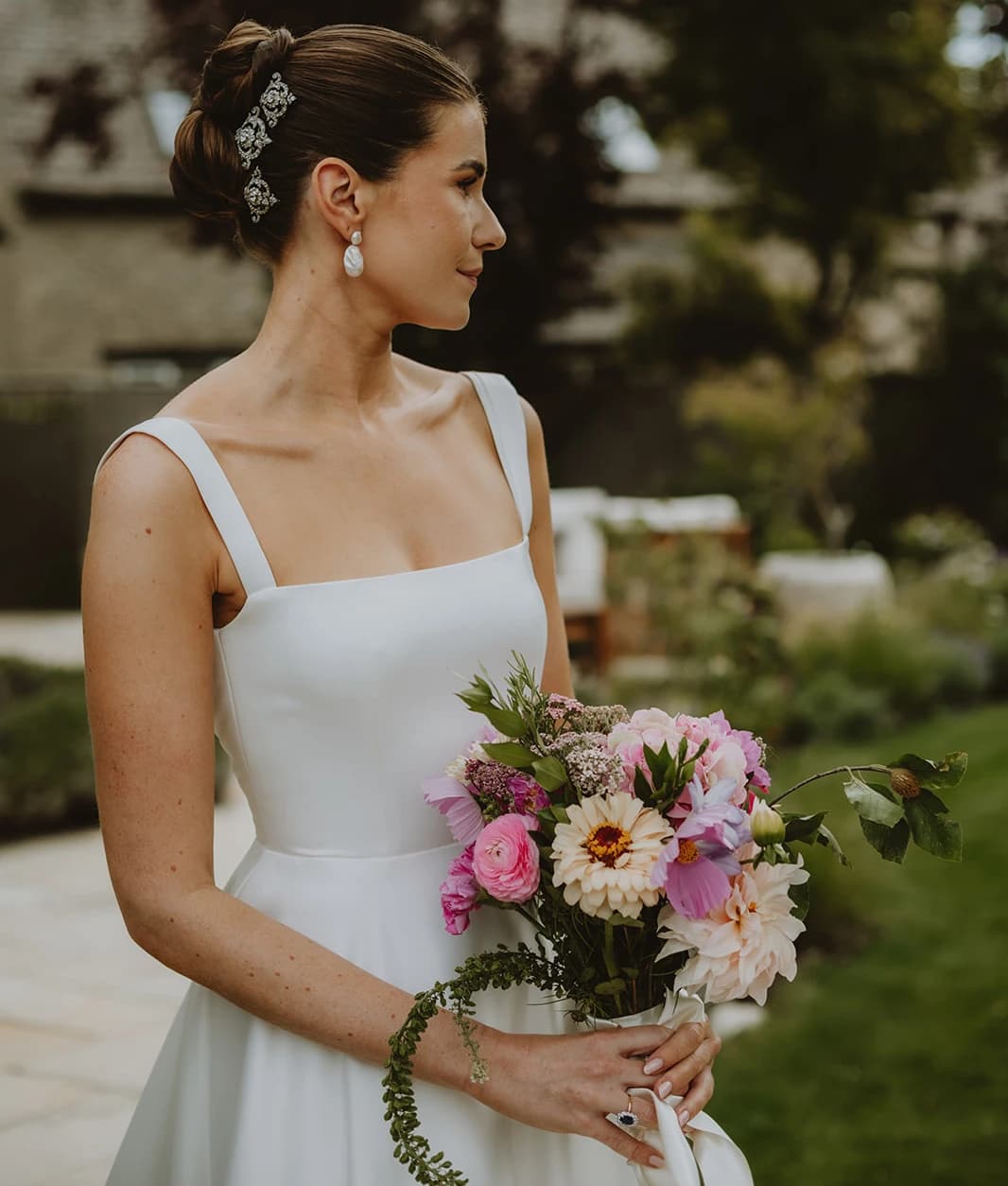 Bride with Cartier tiara brooches in her hair holding a wildflower bouquet in profile