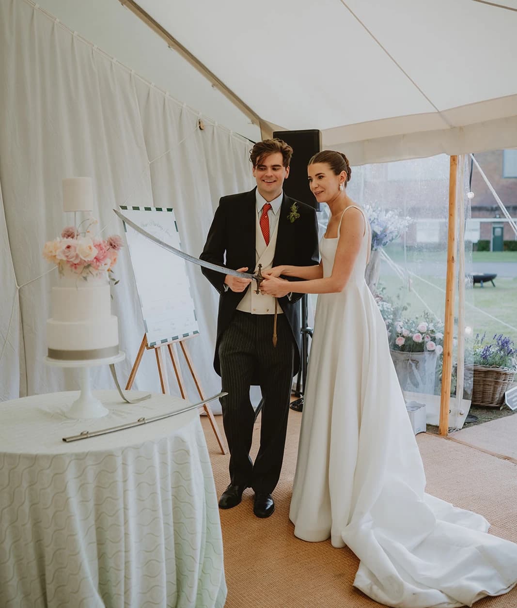 Newlyweds holding the family sword ready to cut the wedding cake