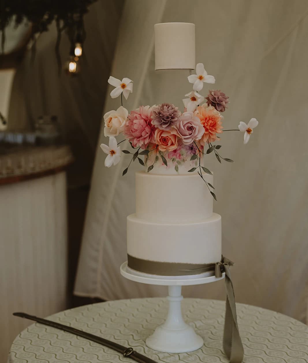 Floating tier wedding cake with sugar flowers beside the family sword