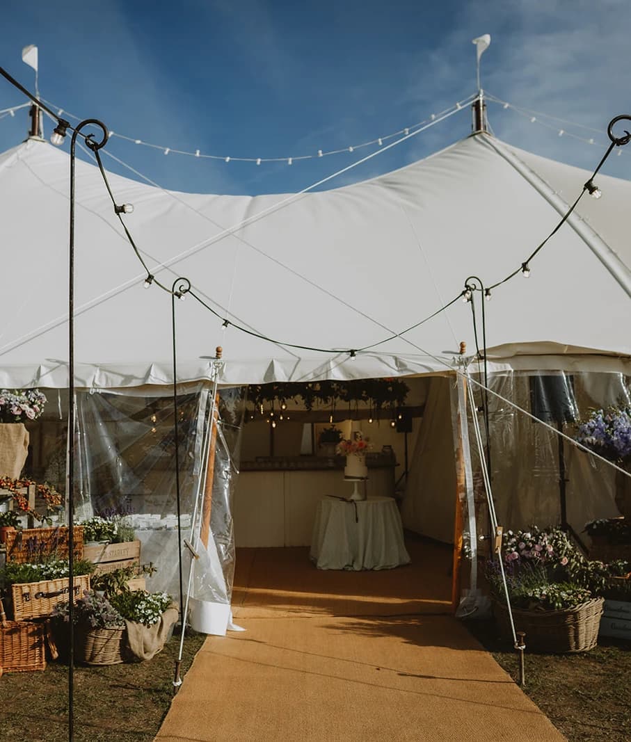 Marquee entrance with festoon lights, flower crates and a walkway into the reception