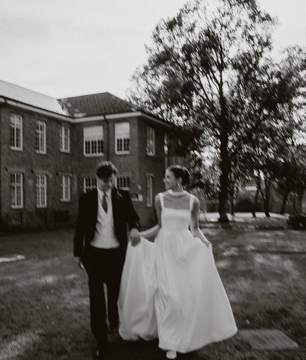 Black and white photograph of the newlyweds walking across the lawn at Bicester Motion