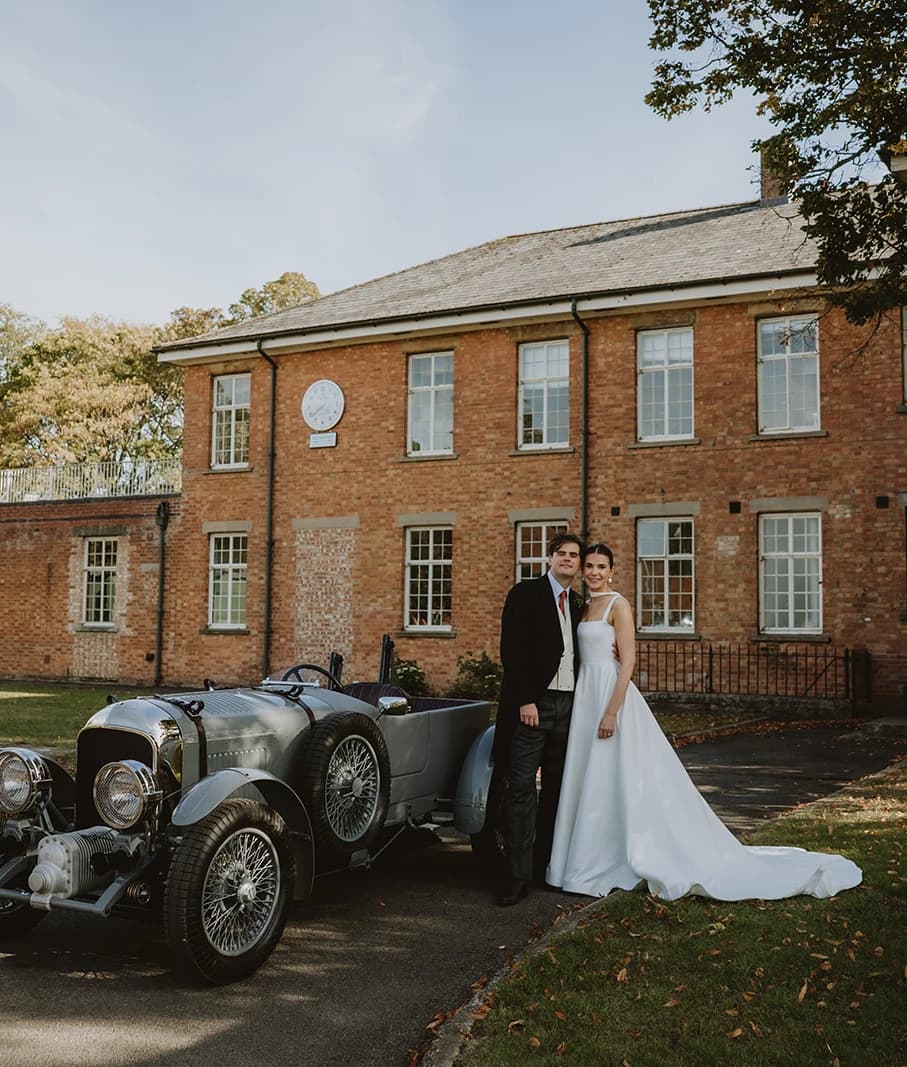 Couple standing beside a grey vintage Bentley at Bicester Motion