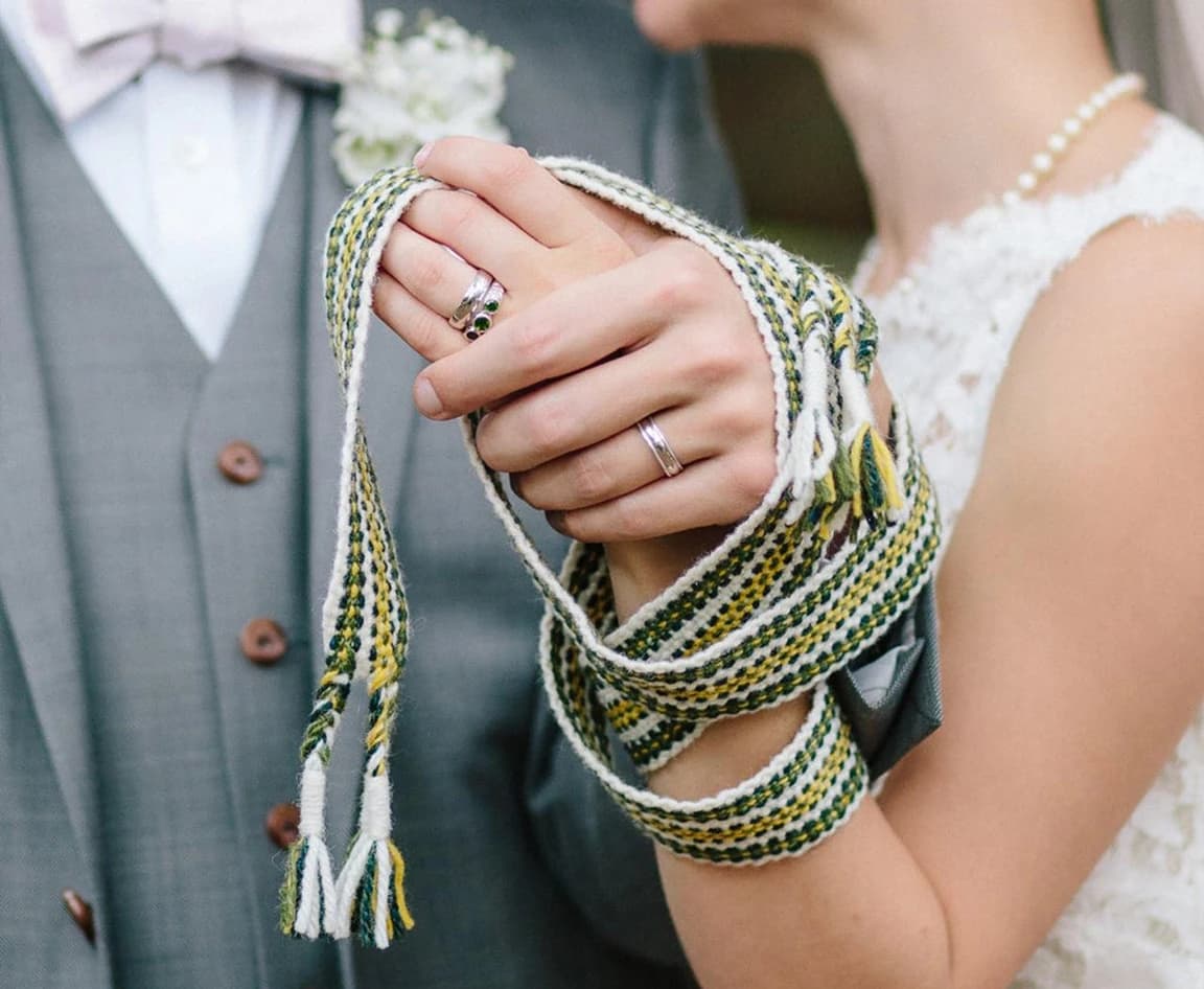 Bride and groom holding hands tied with cord during a handfasting ceremony