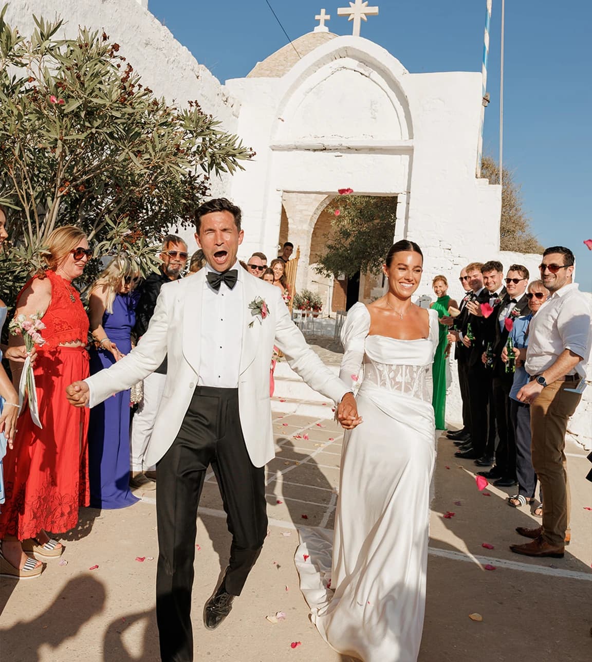 Bride and groom walk from their wedding venue, a Greek church on island