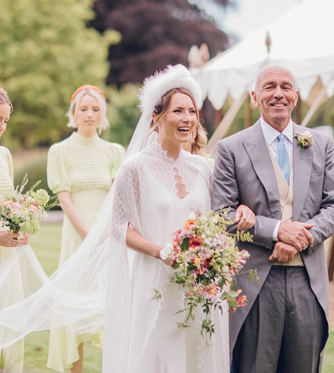 Bride walks down aisle with her father and bridesmaids behind