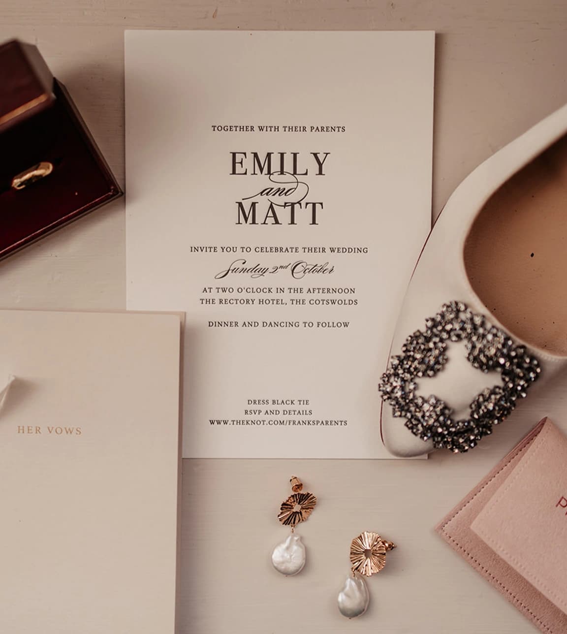 A timeless wedding invite and bride's vows placed next to wedding bands, bride's jewellery and shoes.